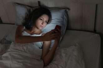 Female using smartphone in bed at night.