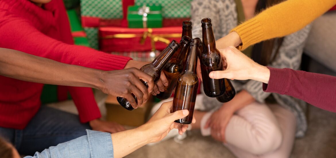 Happy diverse female and male friends toasting with beer at christmas time